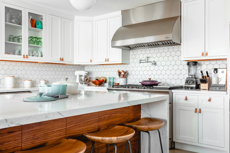 A bright kitchen with a wood island, white cabinetry and copper fixtures