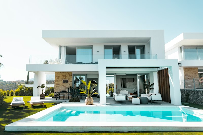 A swimming pool beside a modern home and outdoor seating area