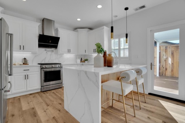 White kitchen with an island, wood floors and pendant lights