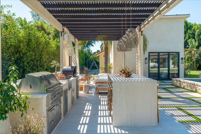 Covered outdoor kitchen and bar beside a pool