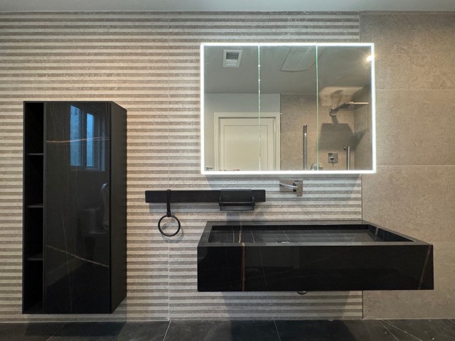 Guest bathroom with large tiles, black vanity and mirror